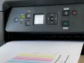 Drukarka Canon wyświetla komunikat "Do którego deseniu jest najbardziej podobny Twój zadrukowany?". Papier z kolorowymi paskami jest częściowo wysunięty.
