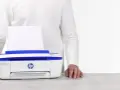 Biała drukarka HP DeskJet 3790 z niebieskimi elementami, z papierem w podajniku. Ułatwia drukowanie, gdy masz instrukcję pod ręką.
