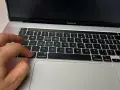 Dłoń naciska klawisz "command" na klawiaturze MacBooka, przygotowując się do instalacji drukarki.