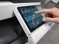 Dotyk palcem na ekranie wielofunkcyjnego urządzenia Konica Minolta C364, wybieranie opcji drukowania.