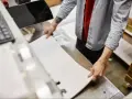 Pracownik przygotowuje arkusze do drukowania na papierze kredowym.