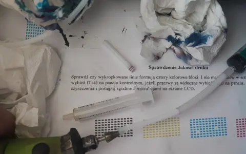 Narzędzia do automatycznego czyszczenia drukarki Brother: strzykawka, papierowe ręczniki z atramentem i instrukcja "Sprawdzenie Jakości druku".