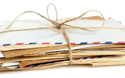 Stos listów w kopertach rozmiar C3, związany sznurkiem. Widać różne rodzaje papieru i ozdobne paski.