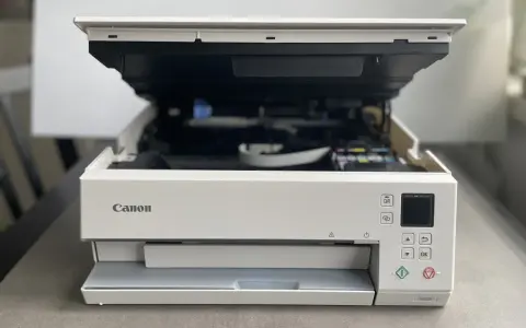Biała drukarka Canon z otwartą pokrywą, widoczne tusze. Poradnik jak zainstalować drukarkę Canon.