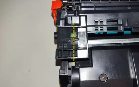 Widok z bliska na chip w tonerze HP, zaznaczony żółtą linią. Pokazuje, jak przełożyć chip w tonerze HP.