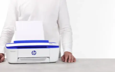Biała drukarka HP DeskJet 3790 z niebieskimi elementami, z papierem w podajniku. Ułatwia drukowanie, gdy masz instrukcję pod ręką.