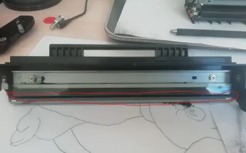 Rozłożony sp112 toner z widocznym wałkiem i resztkami proszku. Czerwona linia zaznacza uszkodzony element.