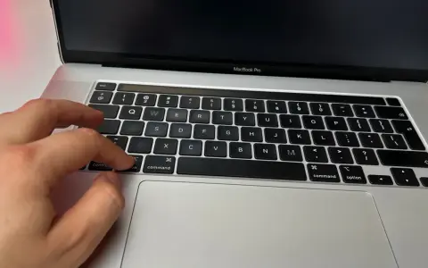 Dłoń naciska klawisz "command" na klawiaturze MacBooka, przygotowując się do instalacji drukarki.