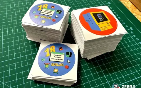 Stosy okrągłych naklejek z motywem retro komputerów i pikselowych postaci. Idealne, by pokazać, jak zrobić naklejki na festiwal informatyczny.