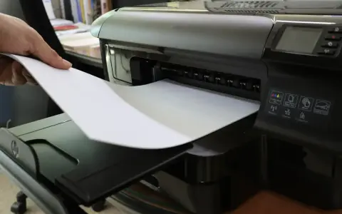 Dłoń wkłada papier do drukarki. To nie jest elementem eksploatacyjnym drukarki laserowej, lecz jej podstawowym materiałem.