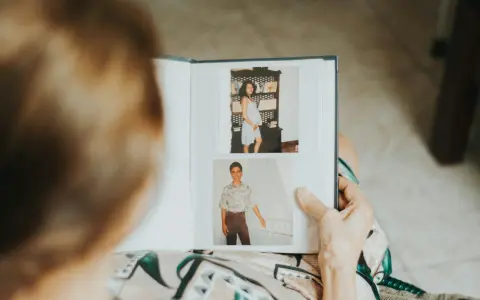 Osoba przegląda fotoksiążkę ze zdjęciami z ciąży i młodzieńczymi portretami. To inspiracja, jak zrobić fotoksiążkę pełną wspomnień.