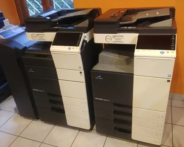 Dwie kserokopiarki Konica Minolta bizhub C454e i C284e stoją obok siebie, gotowe do pracy.