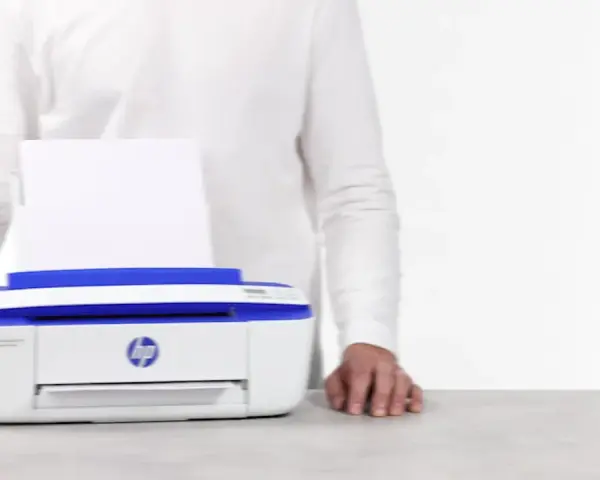 Biała drukarka HP DeskJet 3790 z niebieskimi elementami, z papierem w podajniku. Ułatwia drukowanie, gdy masz instrukcję pod ręką.