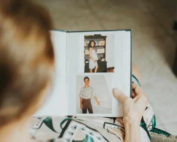 Osoba przegląda fotoksiążkę ze zdjęciami z ciąży i młodzieńczymi portretami. To inspiracja, jak zrobić fotoksiążkę pełną wspomnień.